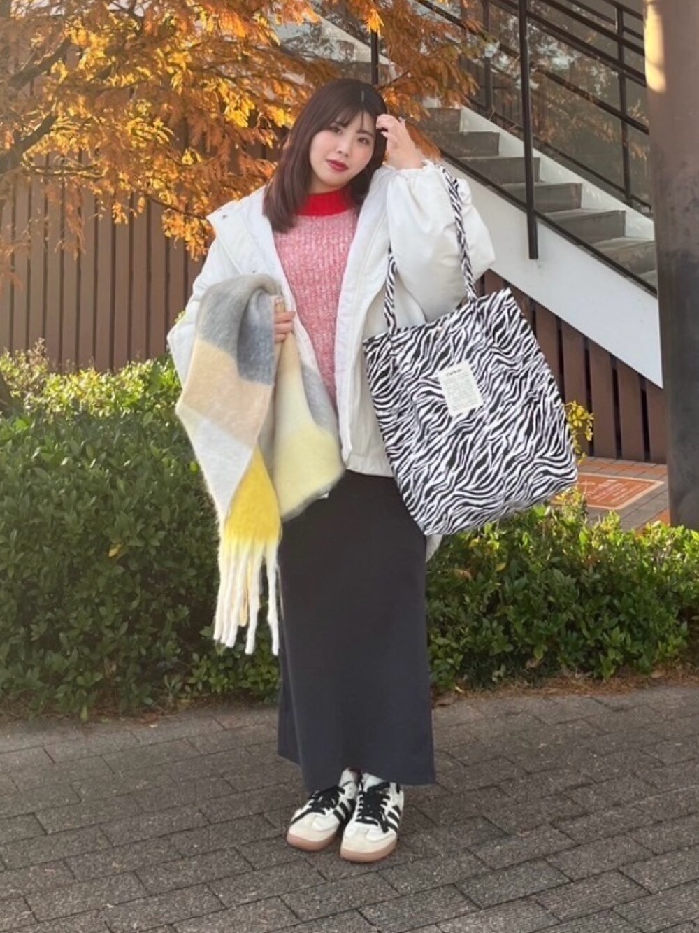 グリーン系のショルダーバッグ、グレー系のスカート、レッド系のニット/セーターを着用したレディースの冬コーディネートの1枚目の写真