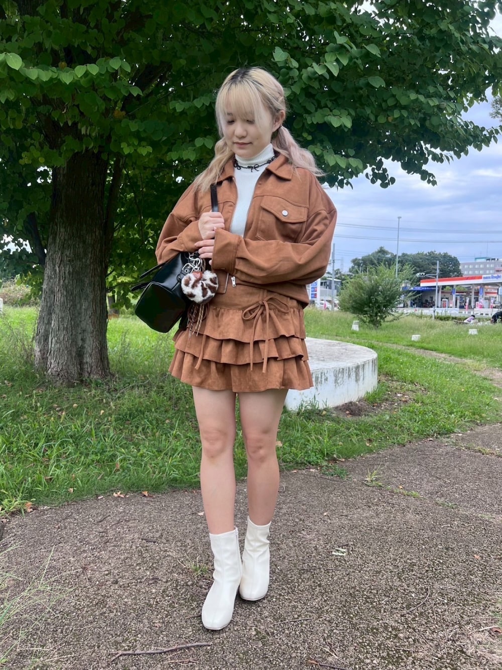 イエロー系のスカート、イエロー系のブルゾン、ホワイト系のブーツを着用したレディースの秋コーディネートの1枚目の写真