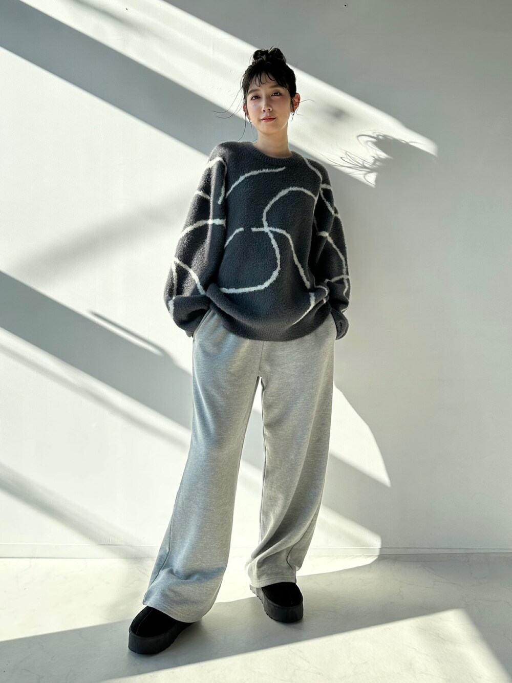 グレー系のスウェットパンツ、ブラック系のブーツ、グレー系のニット/セーターを着用したレディースの秋コーディネートの1枚目の写真