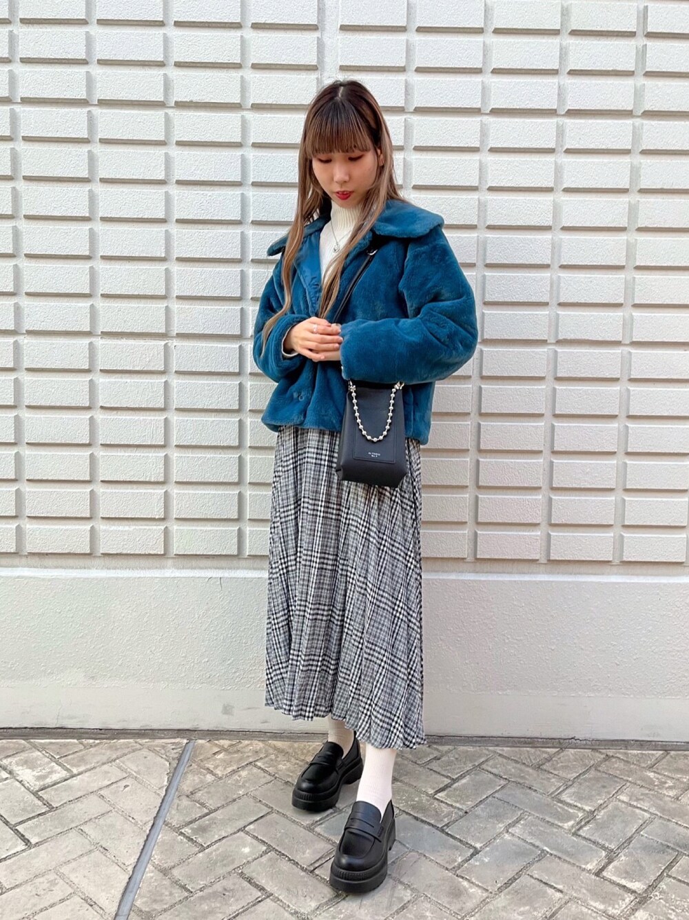 ブラック系のショルダーバッグ、ブラック系のスカートを着用したレディースの冬コーディネートの1枚目の写真