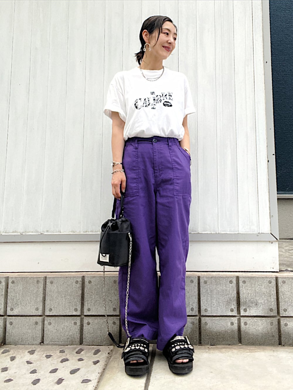 パープル系のカーゴパンツ、ブラック系のサンダル、ブラック系のショルダーバッグを着用したレディースの夏コーディネートの1枚目の写真