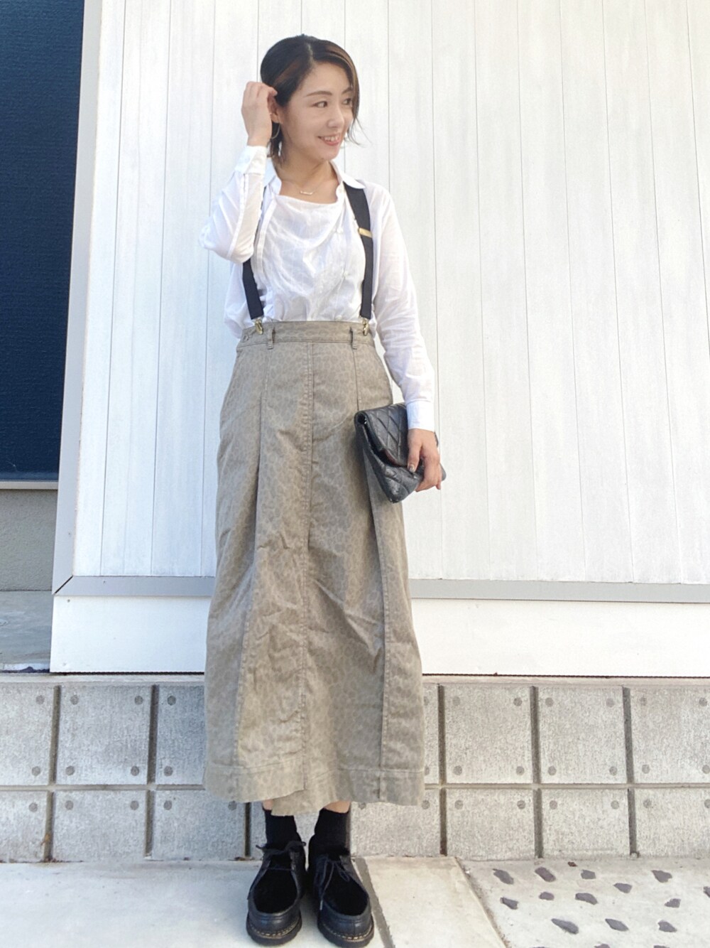 ブラック系のドレスシューズ、ベージュ系のスカート、ブラック系のクラッチバッグを着用したレディースの秋コーディネートの1枚目の写真