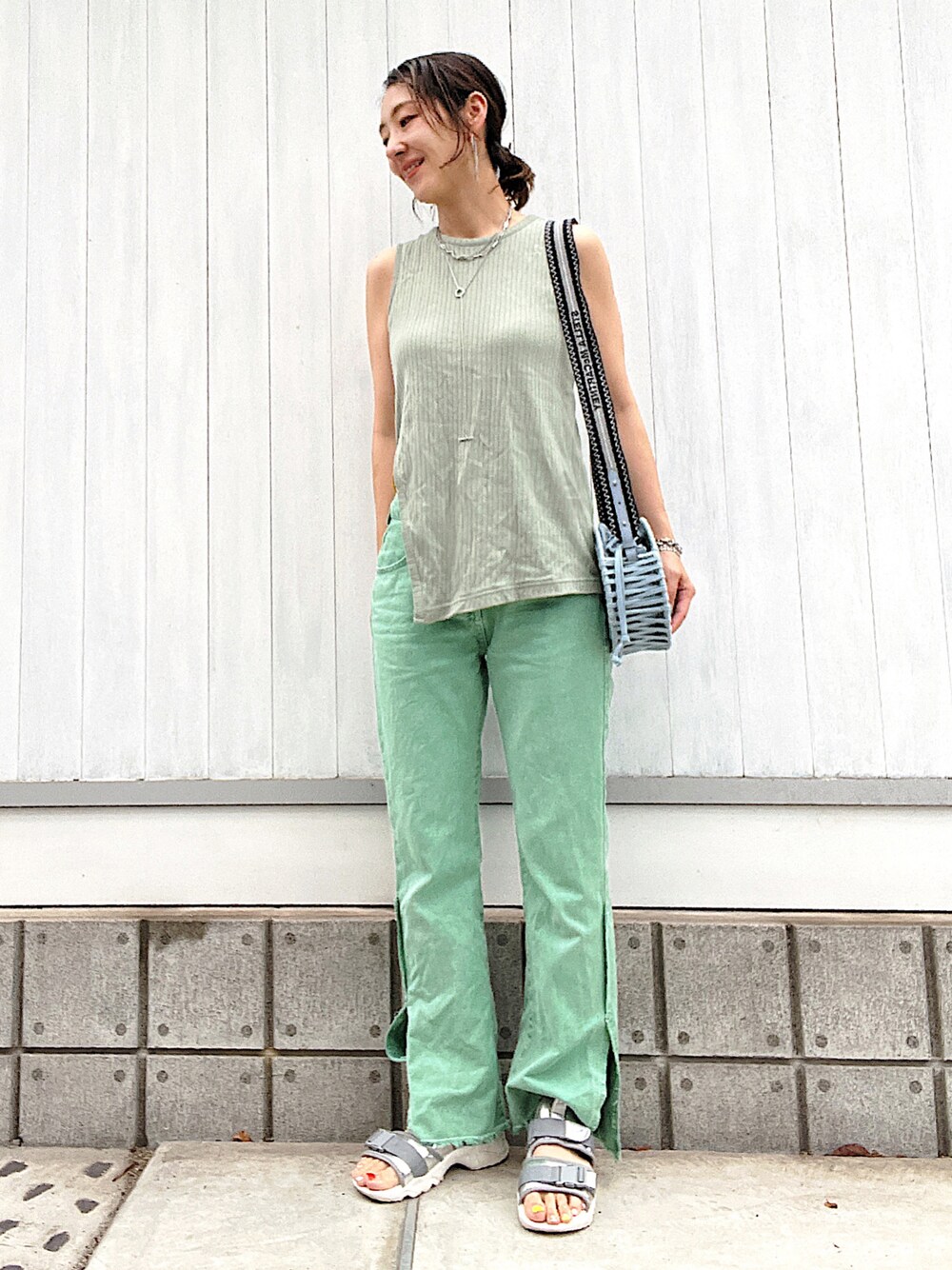 グリーン系のデニムパンツ、シルバー系のサンダル、ブルー系のショルダーバッグを着用したレディースの夏コーディネートの1枚目の写真