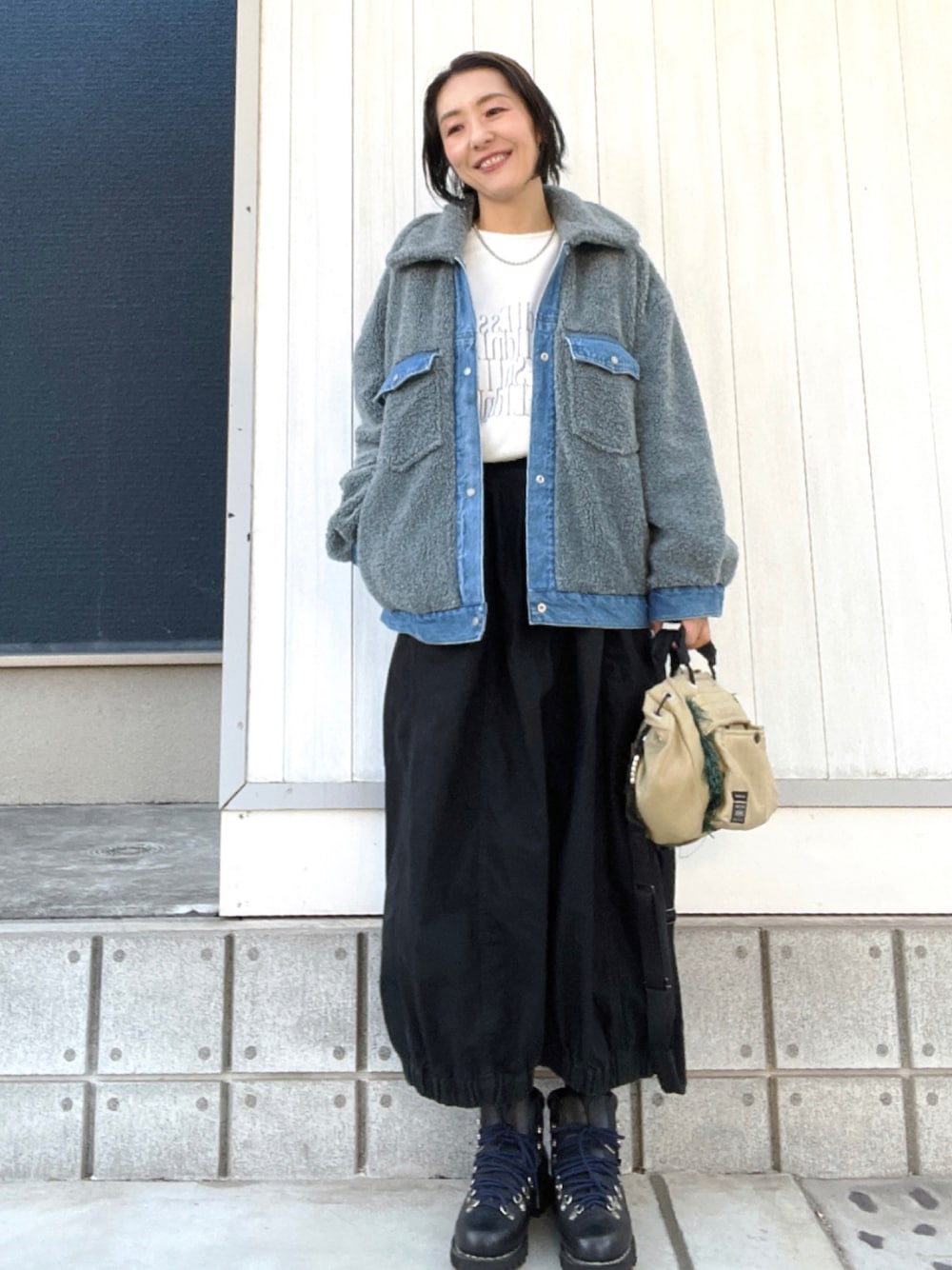 ブルー系のその他アウター、ブラック系のスカート、ブラック系のブーツを着用したレディースの冬コーディネートの1枚目の写真