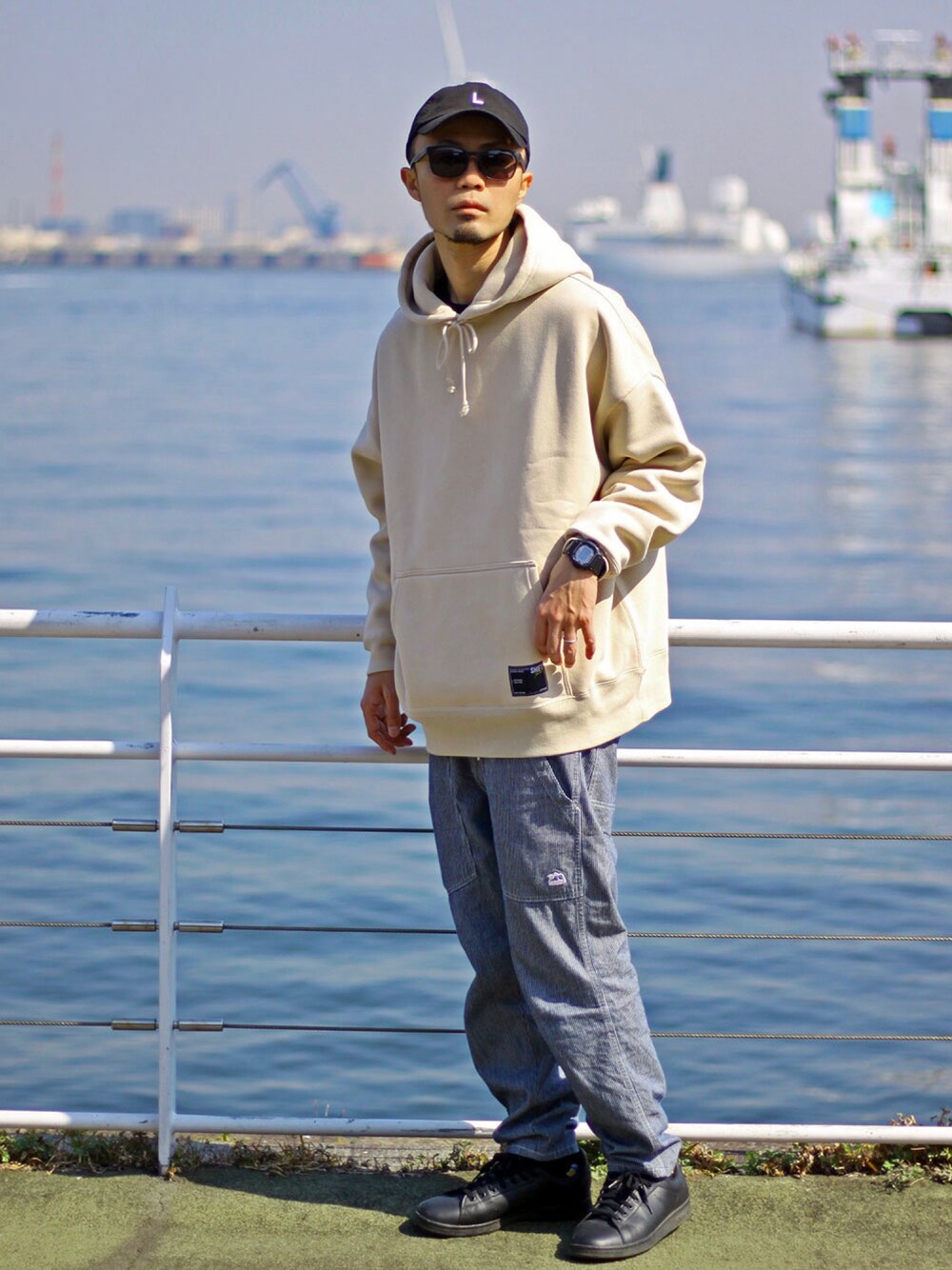 ベージュ系のパーカー、ホワイト系のデニムパンツ、ブラック系のスニーカーを着用したメンズの春コーディネートの1枚目の写真