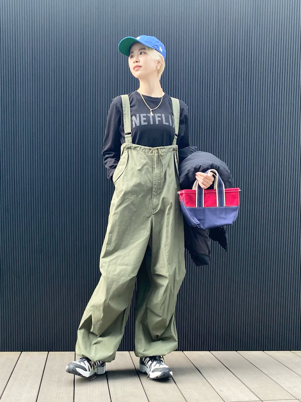 ブラック系のTシャツ/カットソー、グリーン系のサロペット/オーバーオール、レッド系のトートバッグを着用したレディースの冬コーディネートの1枚目の写真