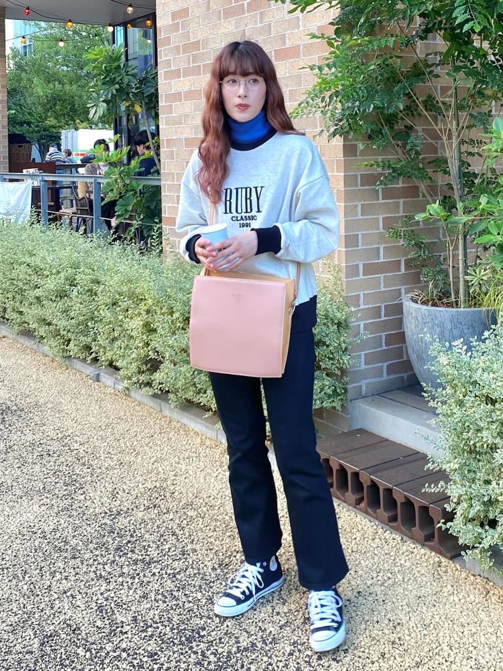 ブラック系のパンツ、ブラック系のスニーカー、ピンク系のショルダーバッグを着用したレディースの秋コーディネートの1枚目の写真