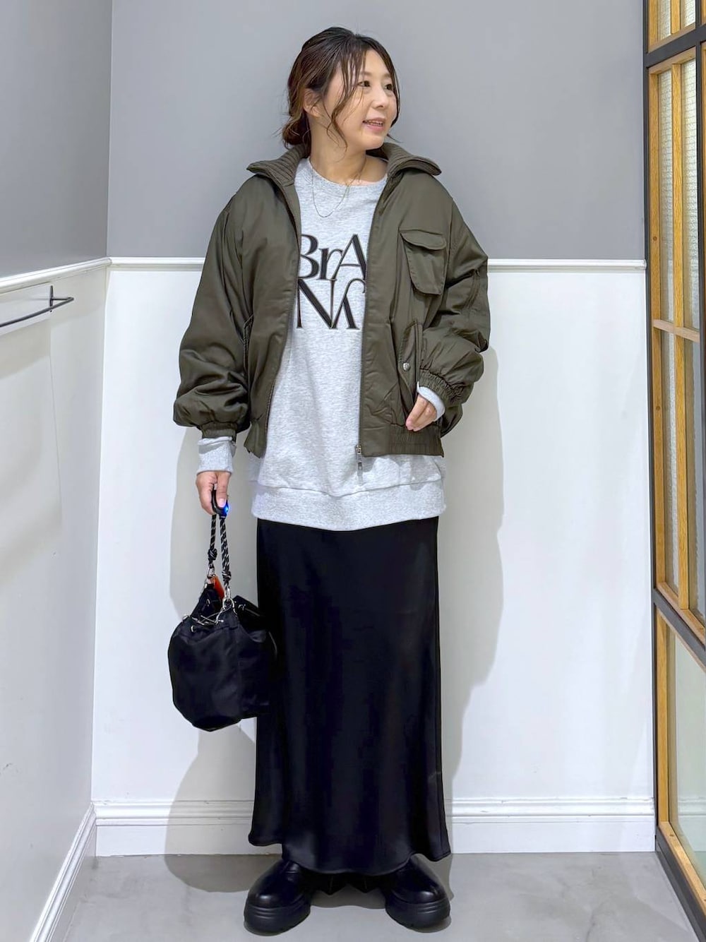 ブラック系のショルダーバッグ、ブラック系のスカート、ブラック系のブーツを着用したレディースの秋コーディネートの1枚目の写真