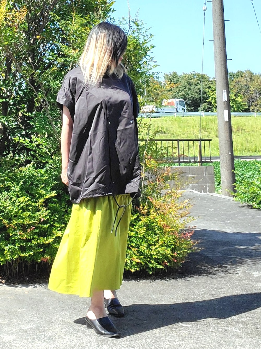 ブラック系のパンプス、グリーン系のスカート、ブラック系のその他アウターを着用したレディースの秋コーディネートの1枚目の写真