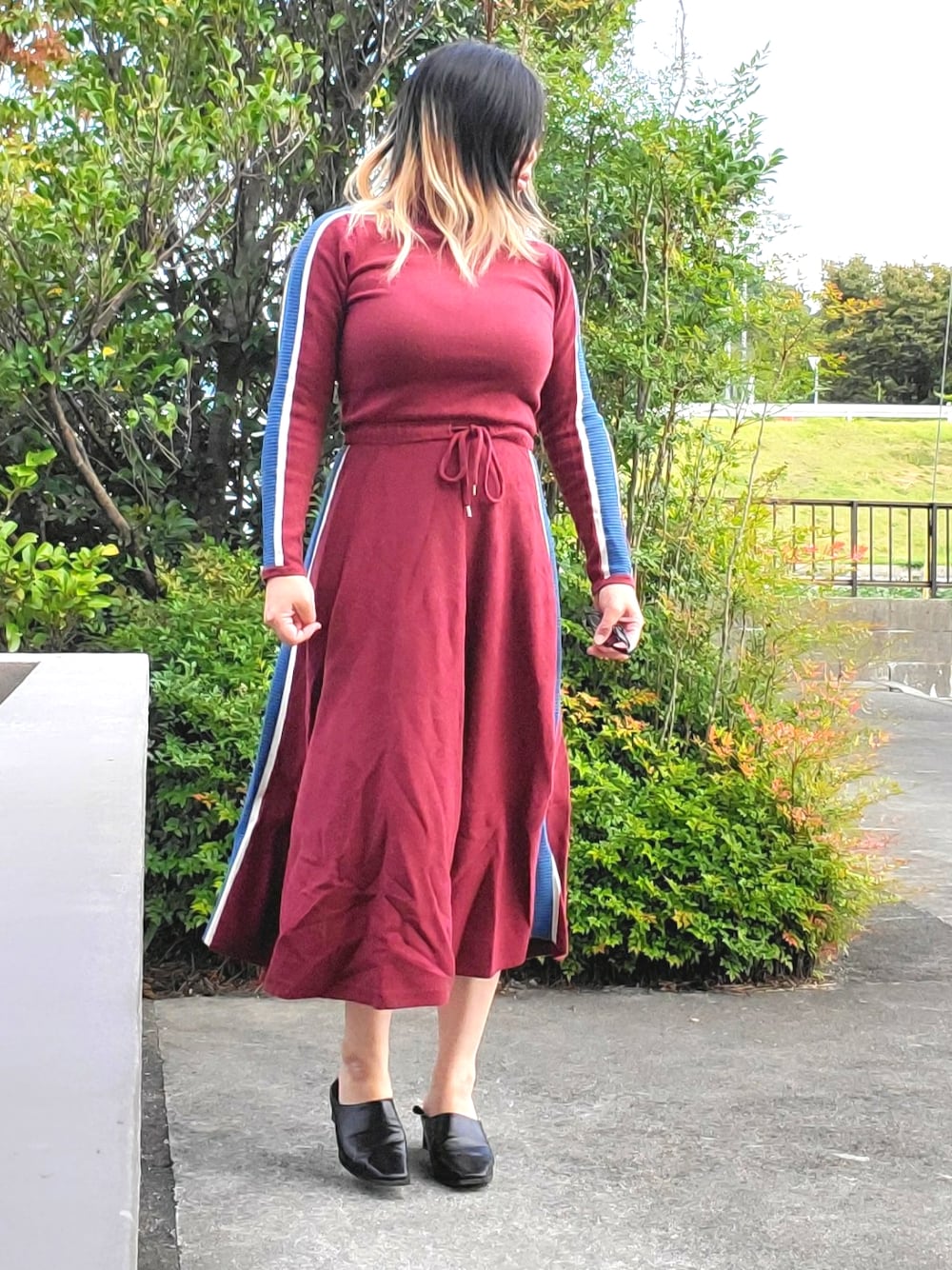 レッド系のワンピース、ブラック系のパンプスを着用したレディースの秋コーディネートの1枚目の写真