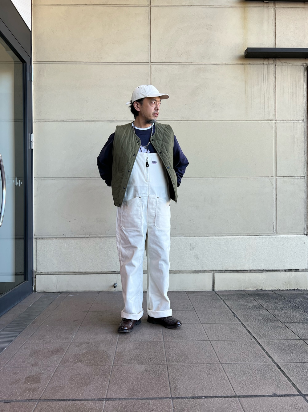 ホワイト系のサロペット/オーバーオール、グリーン系のベストを着用したメンズの冬コーディネートの1枚目の写真