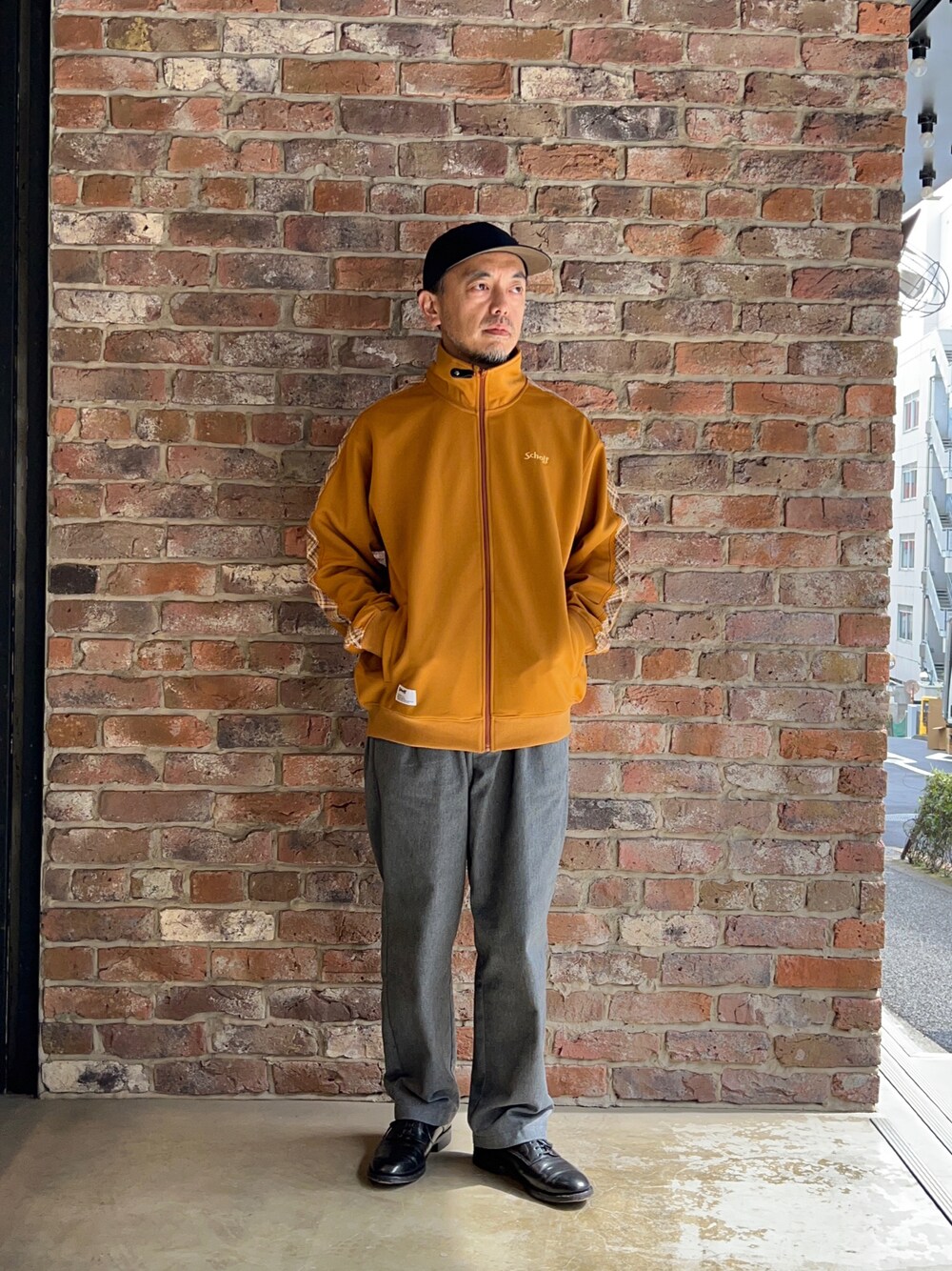 ブラック系のデニムパンツ、オレンジ系のブルゾンを着用したメンズの春コーディネートの1枚目の写真
