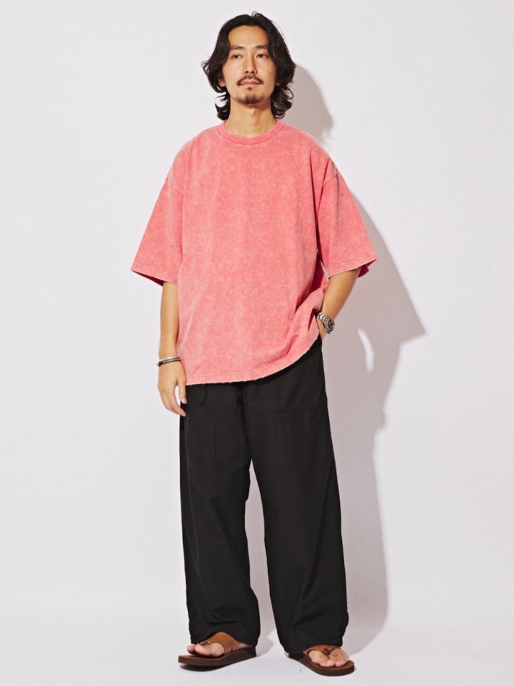 ブラウン系のサンダル、ピンク系のTシャツ/カットソー、ブラック系のカーゴパンツを着用したメンズの夏コーディネートの1枚目の写真