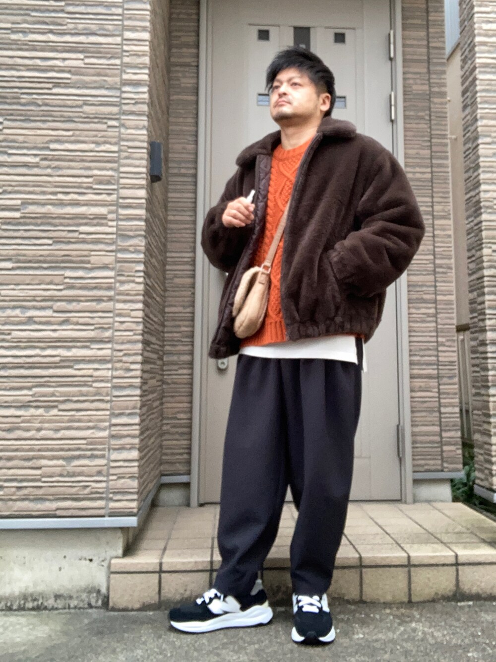グレー系のその他パンツ、ブラック系のスニーカー、オレンジ系のニット/セーターを着用したメンズの冬コーディネートの1枚目の写真