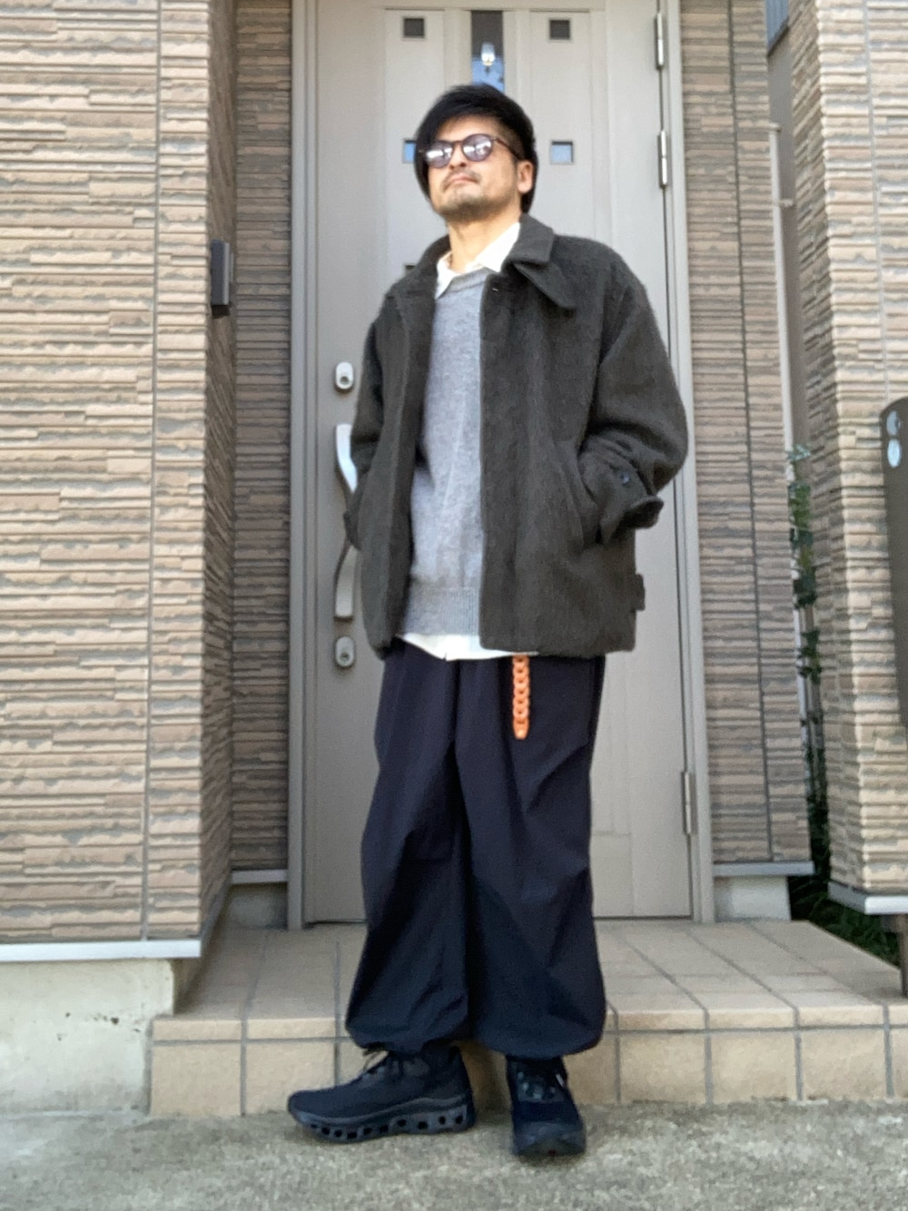 「冬コーデ、ニット、ニットベスト、レイヤードスタイル、カーキ、テックウェア、テックパンツ、スニーカー、on、きれいめカジュアル」｜「OnのOn Cloudmonster / オン クラウドモンスター（スニーカー、ブラック系）」を使った、タルナンドさん（メンズ・165cm）の冬コーディネートの1枚目の写真