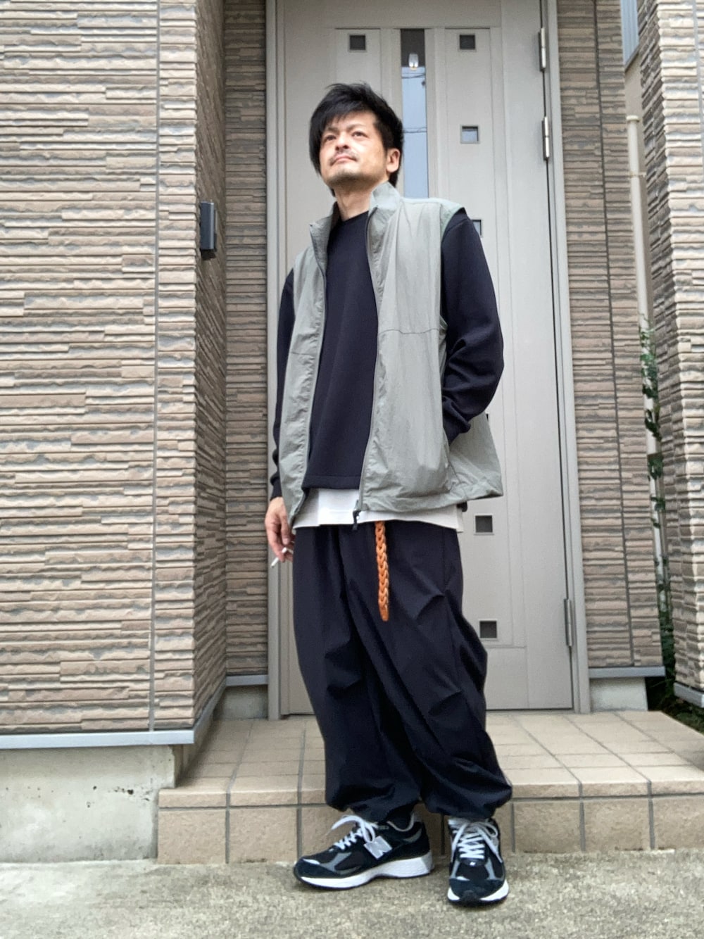 ブラック系のスニーカー、ブラック系のその他パンツ、グリーン系のベストを着用したメンズの春コーディネートの1枚目の写真