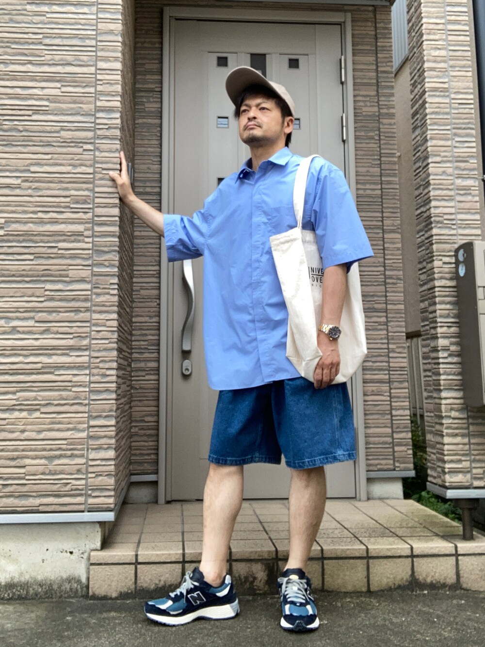 ブルー系のスニーカー、ブルー系のデニムパンツ、ホワイト系のトートバッグを着用したメンズの夏コーディネートの1枚目の写真