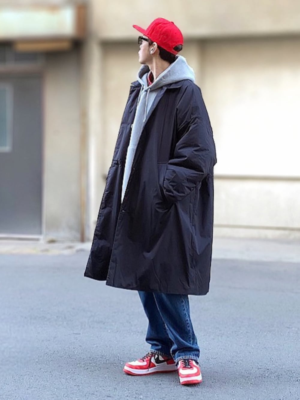 レッド系のスニーカー、ブルー系のデニムパンツ、レッド系のキャップを着用したメンズの冬コーディネートの1枚目の写真