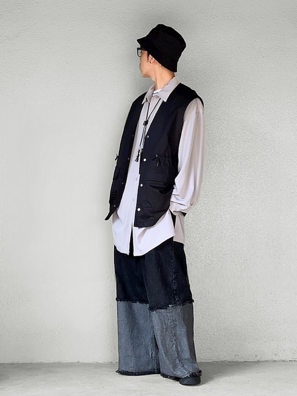 ブラック系のベスト、ブラック系のデニムパンツ、ブラック系のスニーカーを着用したメンズの秋コーディネートの1枚目の写真