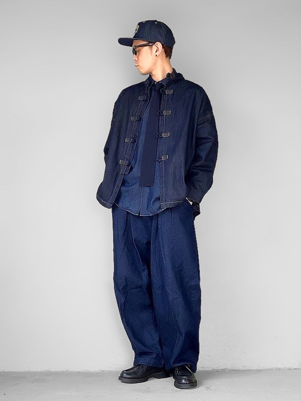 ブルー系のデニムジャケット、ブラック系のドレスシューズ、ブルー系のキャップを着用したメンズの春コーディネートの1枚目の写真