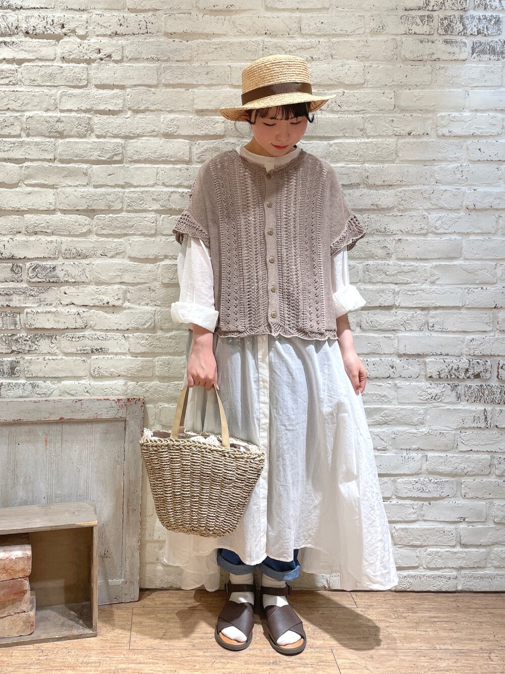 ブラック系のベスト、ホワイト系のワンピース、ベージュ系のハンドバッグを着用したレディースの春コーディネートの1枚目の写真