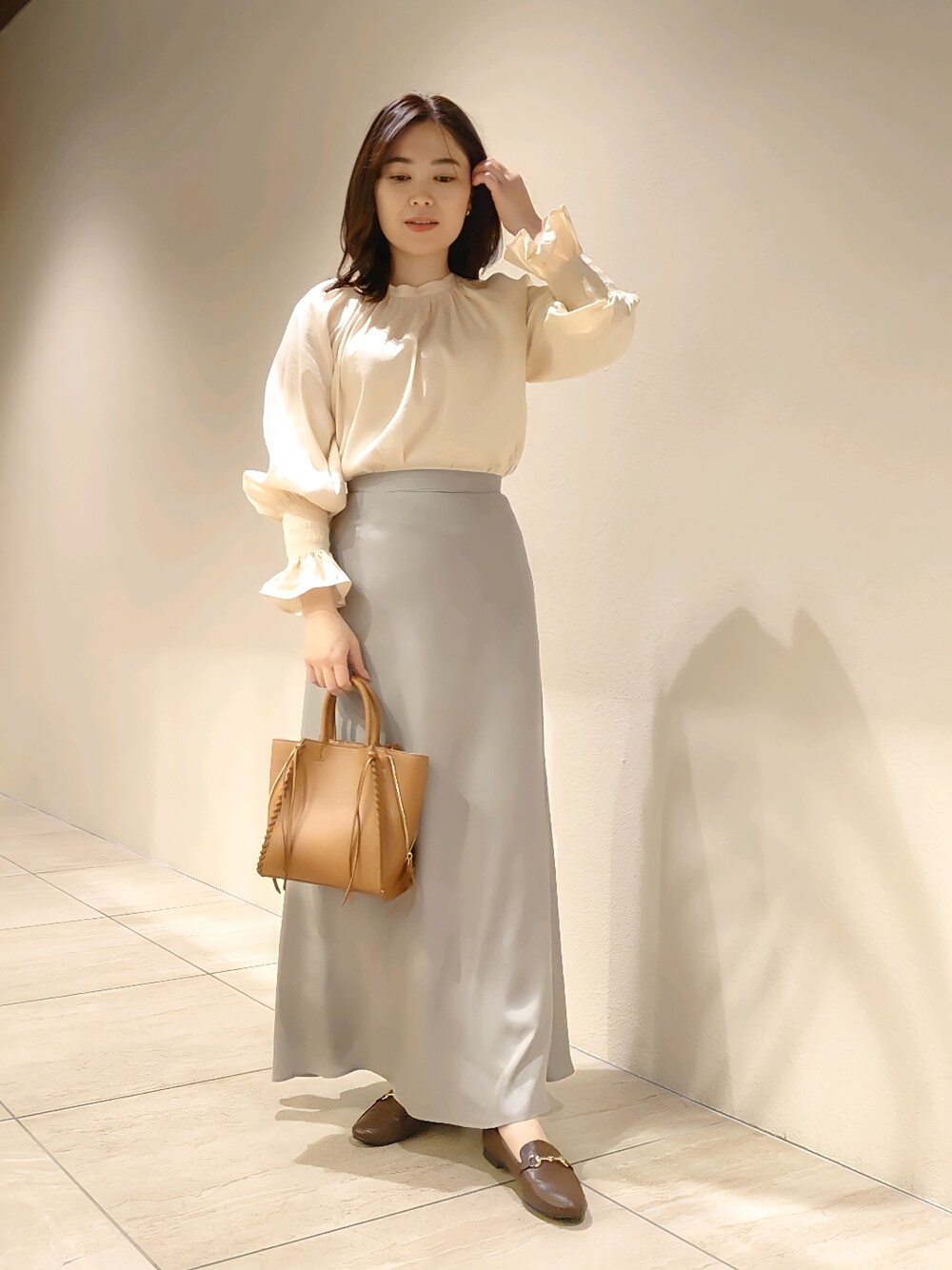 ベージュ系のシャツ/ブラウス、グリーン系のスカート、イエロー系のトートバッグを着用したレディースの冬コーディネートの2枚目の写真