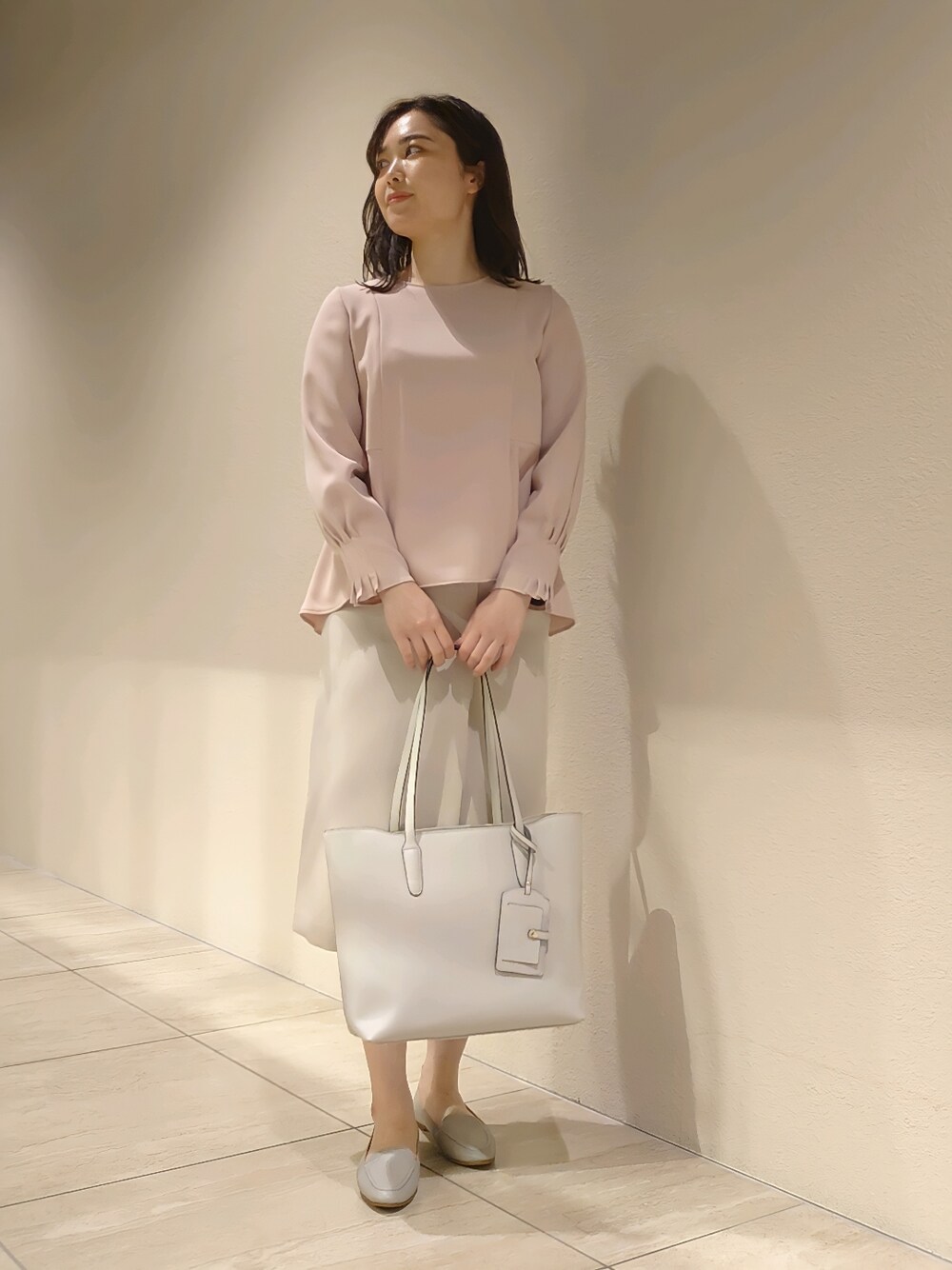 ピンク系のシャツ/ブラウス、ベージュ系のスカート、グレー系のトートバッグを着用したレディースの冬コーディネートの2枚目の写真