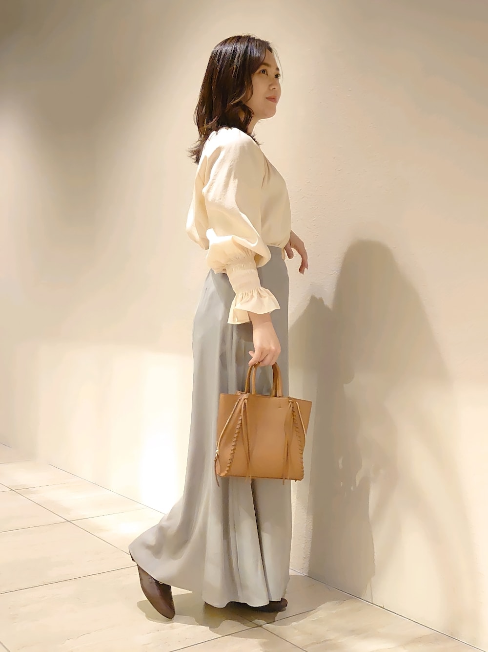 ベージュ系のシャツ/ブラウス、グリーン系のスカート、イエロー系のトートバッグを着用したレディースの冬コーディネートの3枚目の写真