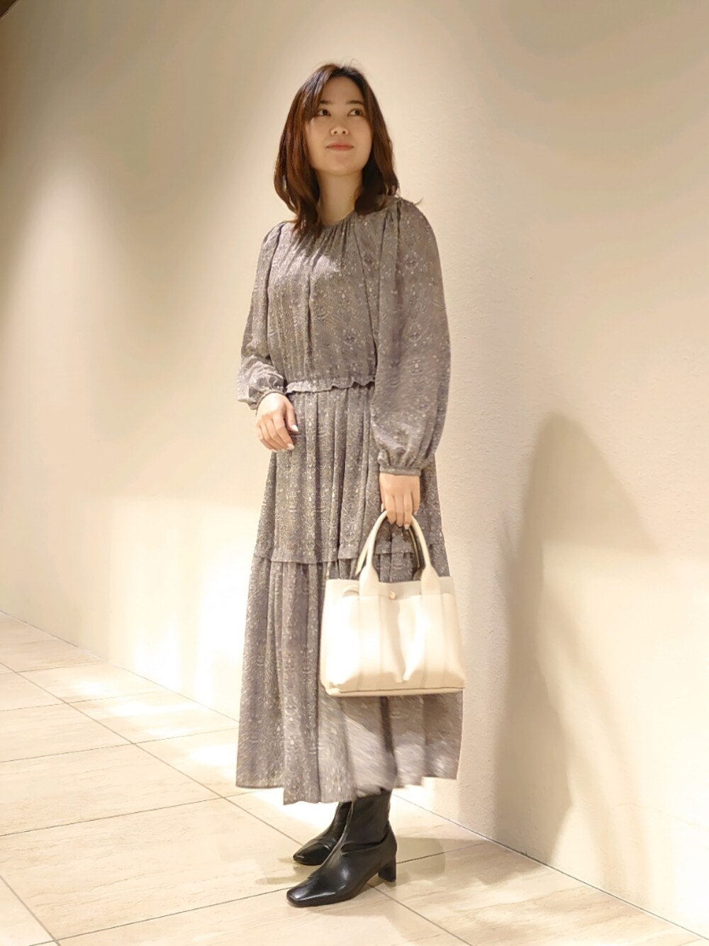 グレー系のワンピース、ホワイト系のトートバッグ、ブラック系のブーツを着用したレディースの冬コーディネートの1枚目の写真