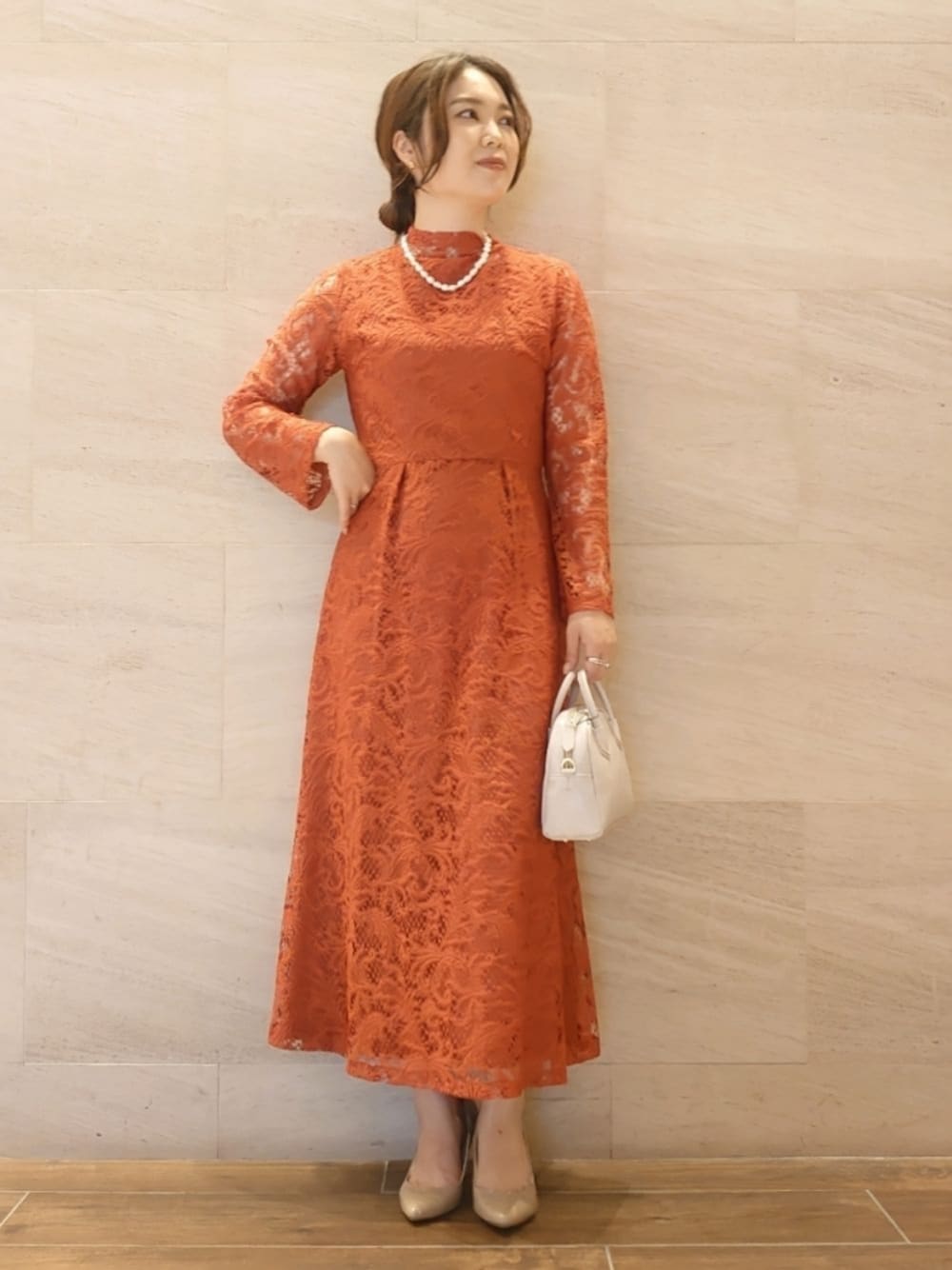 グレー系のショルダーバッグ、ベージュ系のシューズ、レッド系のドレスを着用したレディースの秋コーディネートの1枚目の写真