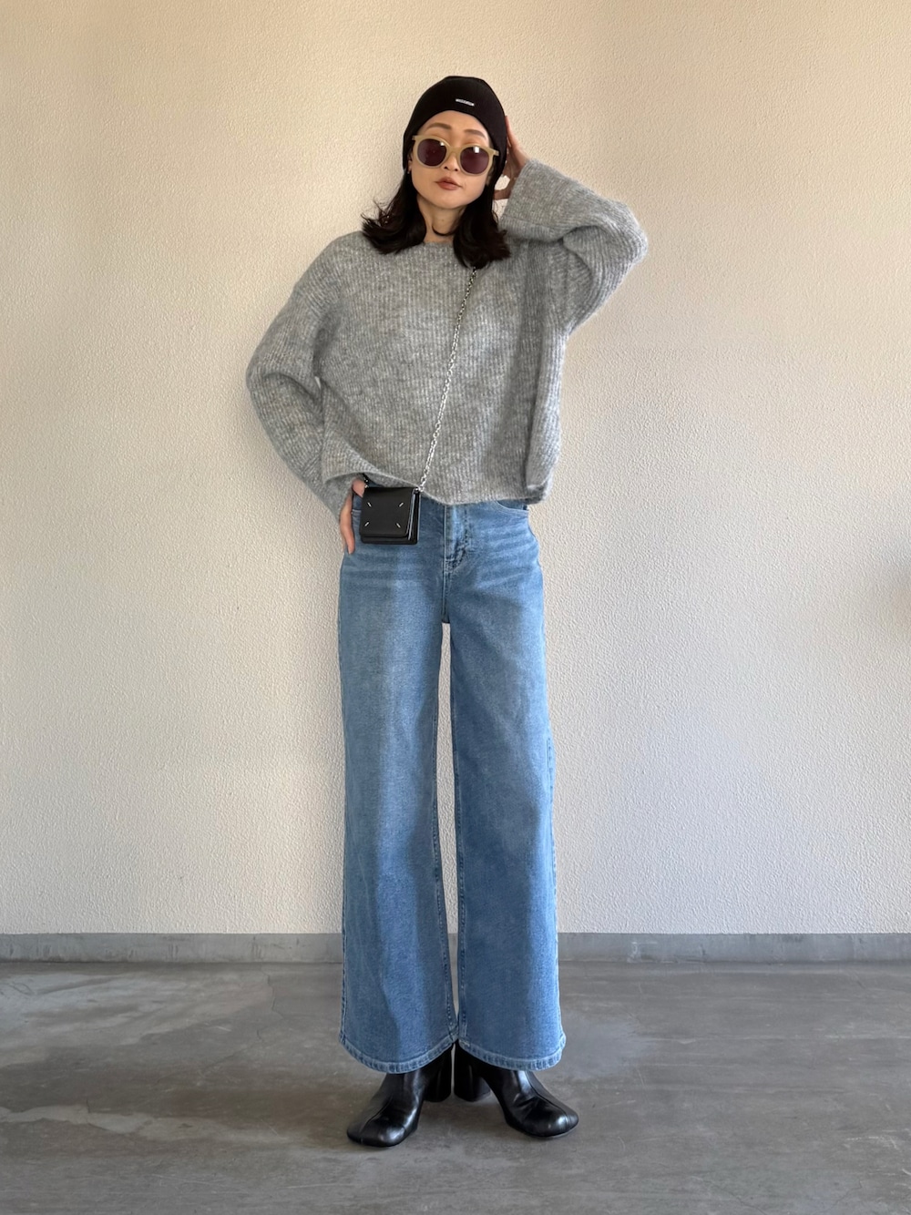 ブルー系のデニムパンツ、グレー系のニット/セーターを着用したレディースの冬コーディネートの1枚目の写真