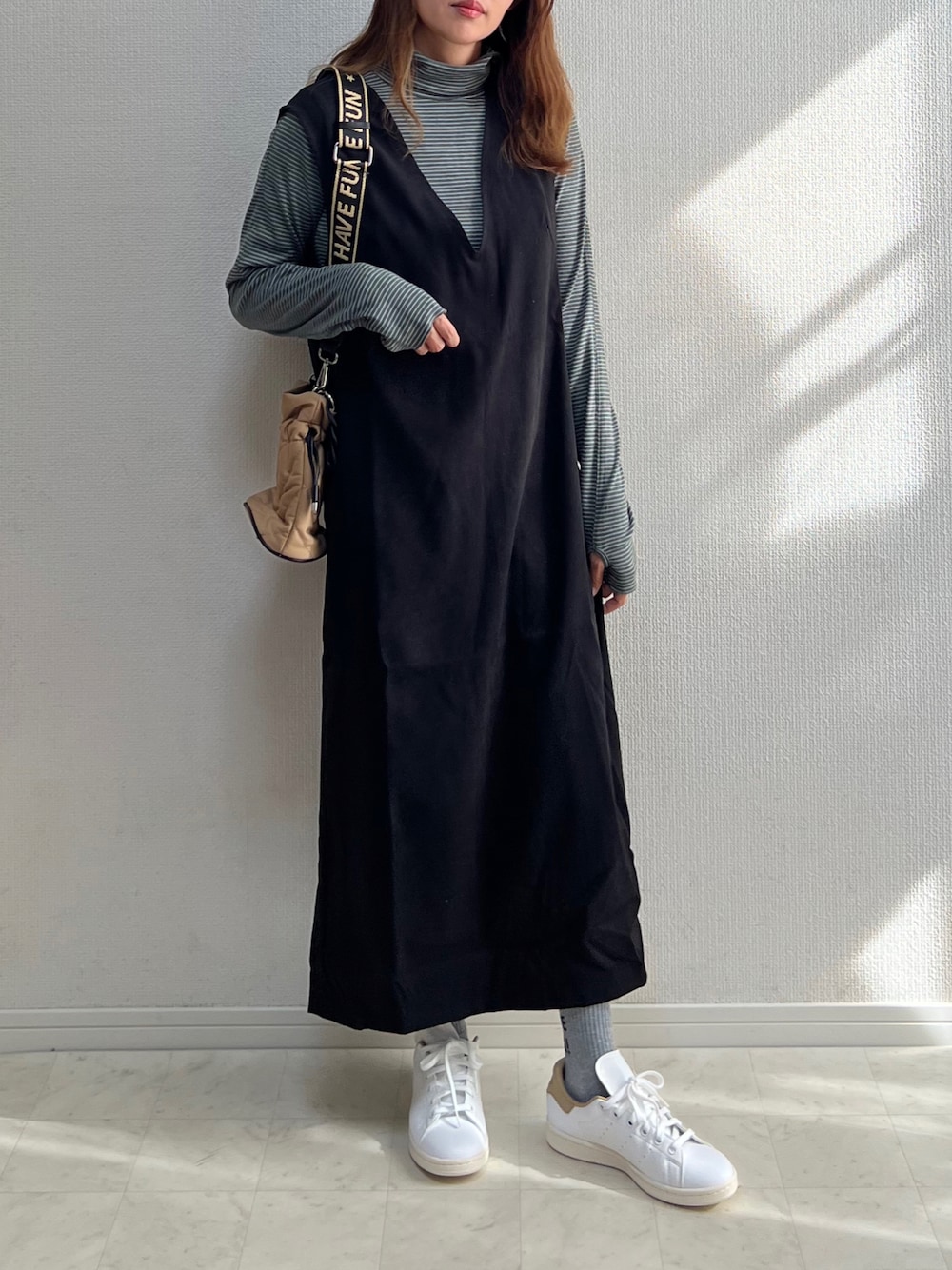 ブラック系のジャンパースカート、ホワイト系のスニーカーを着用したレディースの秋コーディネートの1枚目の写真