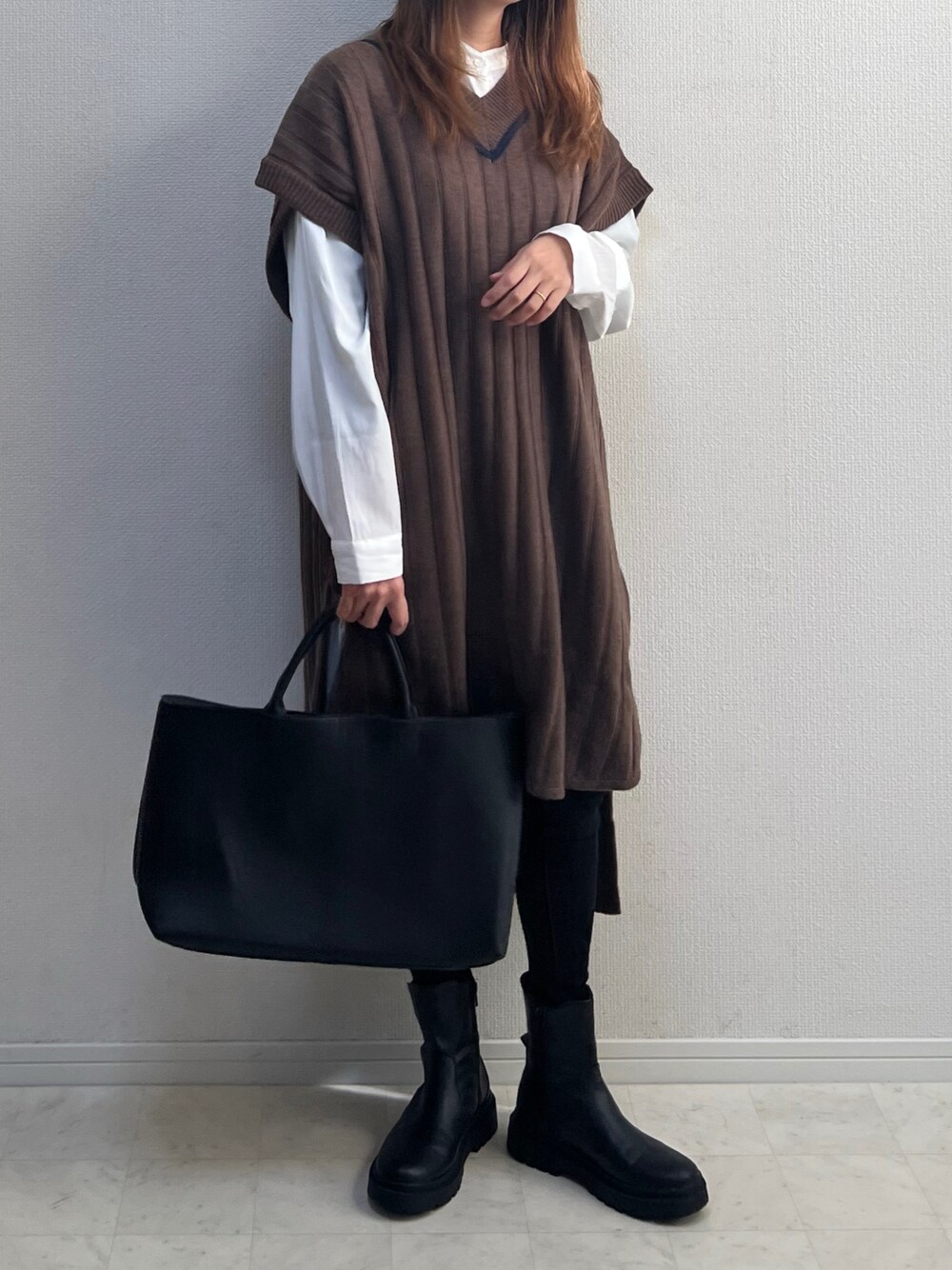 ブラウン系のベストを着用したレディースの冬コーディネートの1枚目の写真