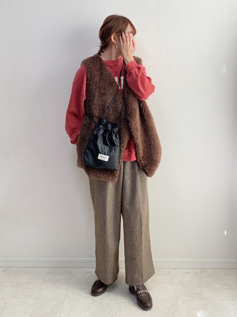 ブラウン系のベスト、ブラック系のショルダーバッグ、ブラウン系のパンツを着用したレディースの冬コーディネートの1枚目の写真