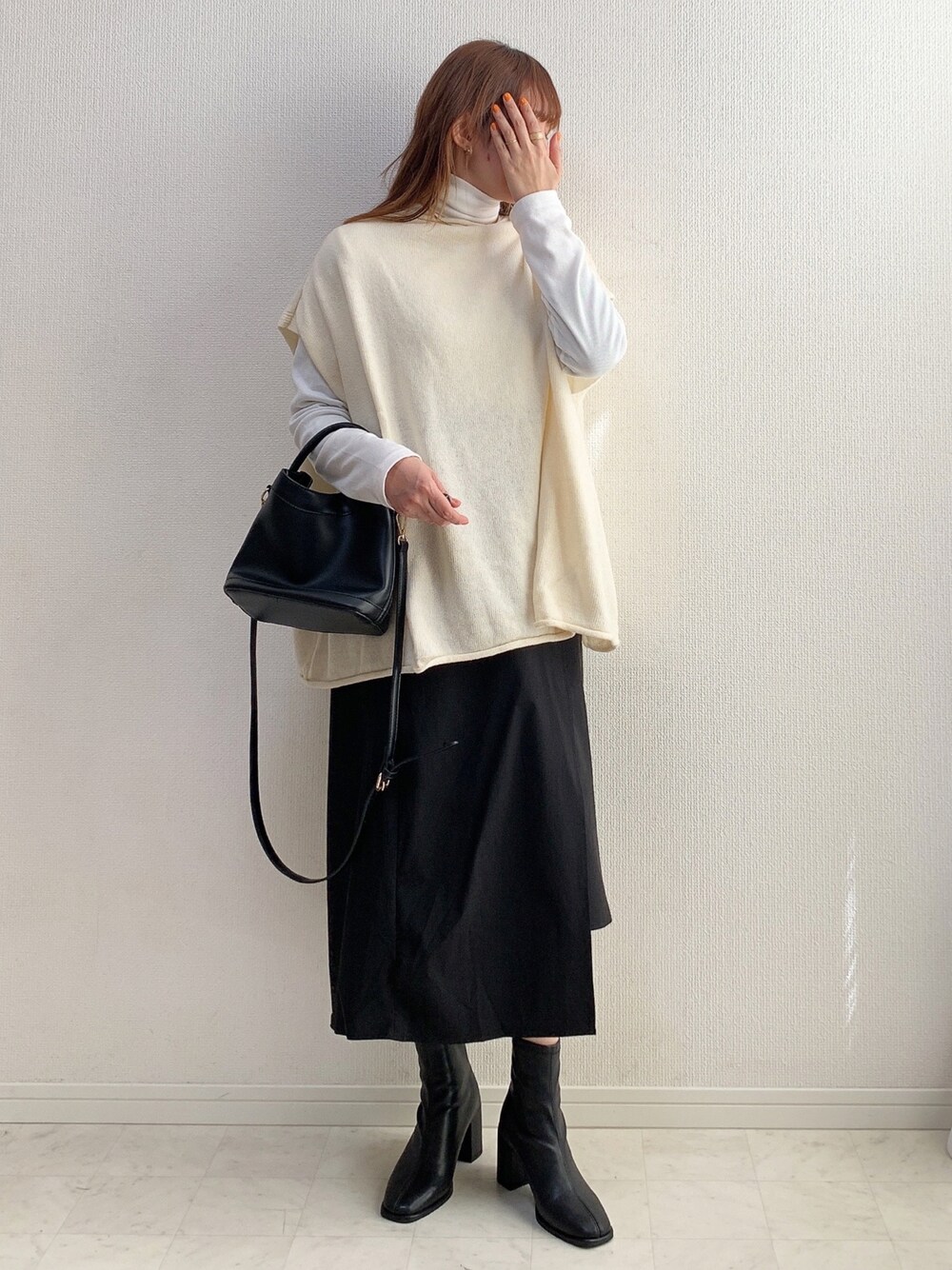 ホワイト系のベスト、ブラック系のスカート、ブラック系のブーツを着用したレディースの冬コーディネートの1枚目の写真