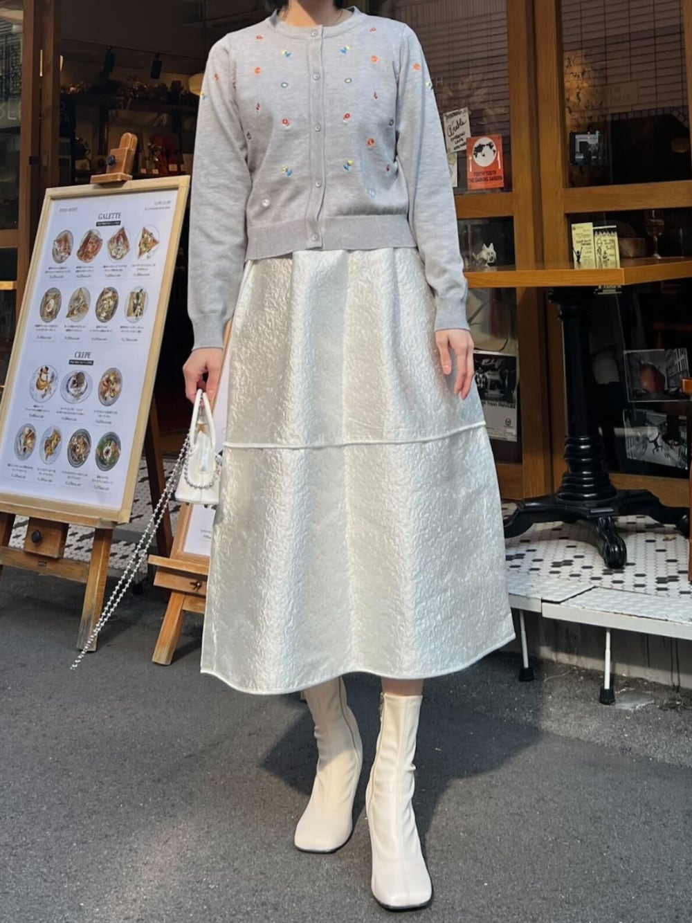 グレー系のカーディガン/ボレロ、ホワイト系のスカートを着用したレディースの冬コーディネートの1枚目の写真
