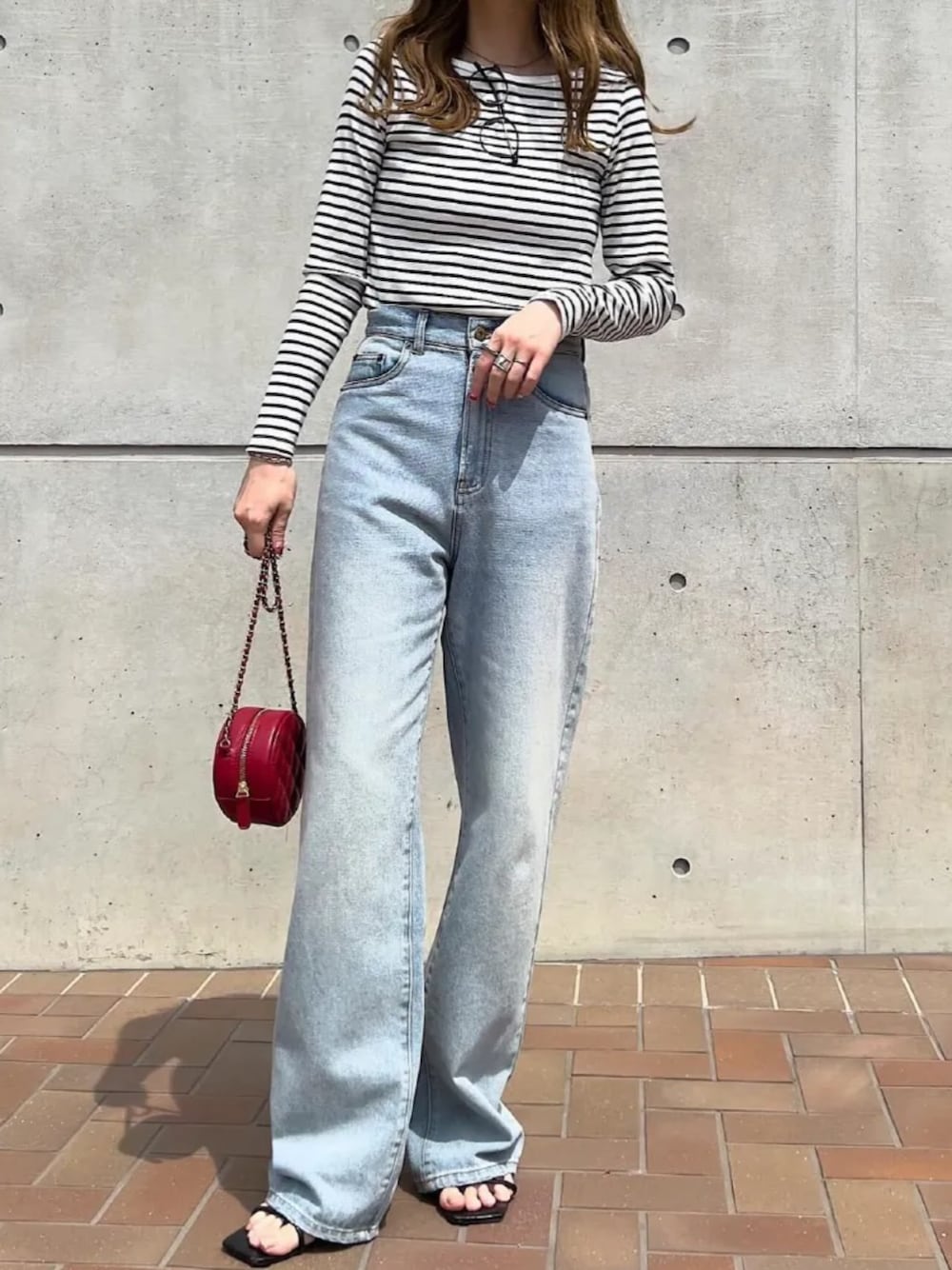 レッド系のショルダーバッグ、ブルー系のデニムパンツを着用したレディースの夏コーディネートの1枚目の写真