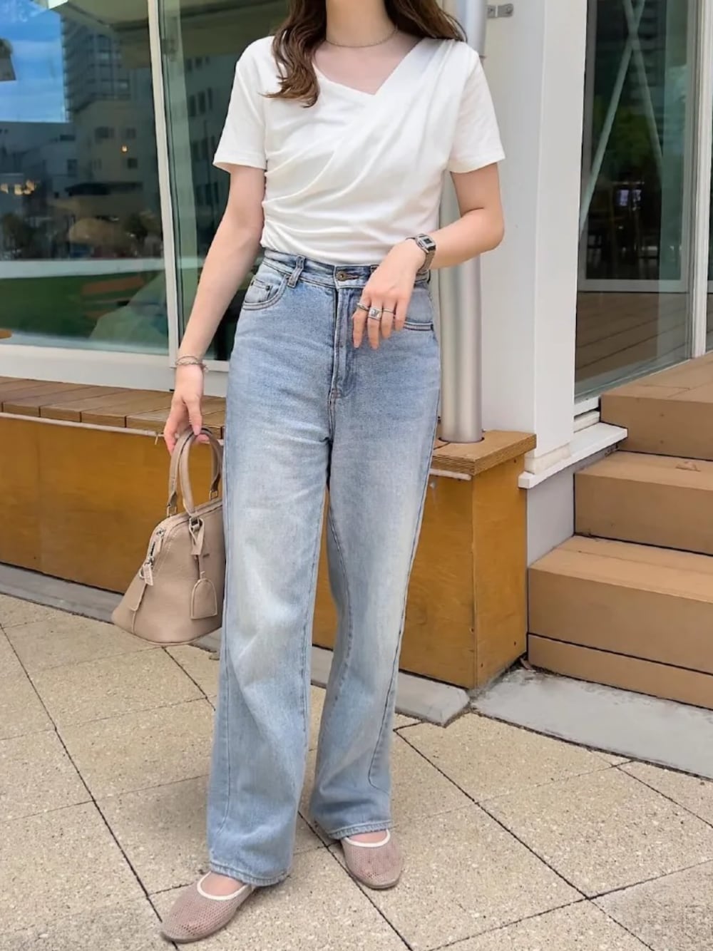 ブルー系のデニムパンツ、ベージュ系のハンドバッグ、ホワイト系のTシャツ/カットソーを着用したレディースの秋コーディネートの1枚目の写真