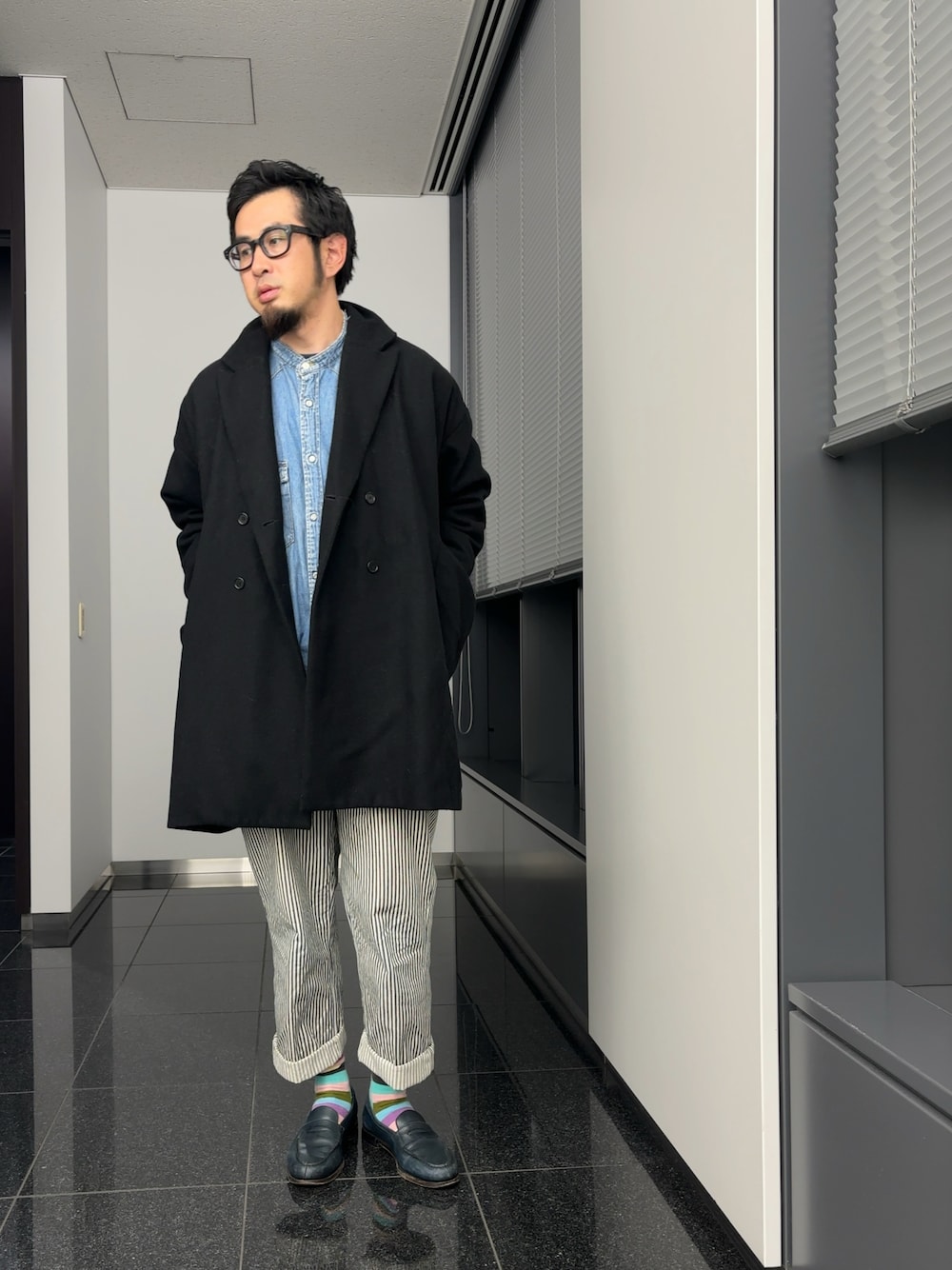 ブラック系のチェスターコート、ブルー系のシャツ/ブラウス、ホワイト系のパンツを着用したメンズの秋コーディネートの1枚目の写真