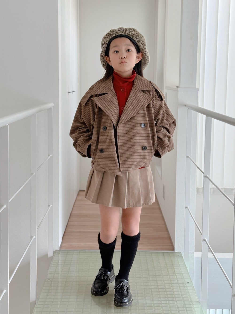 ブラック系のローファー、ブラウン系のトレンチコート、ベージュ系のスカートを着用したキッズの冬コーディネートの1枚目の写真