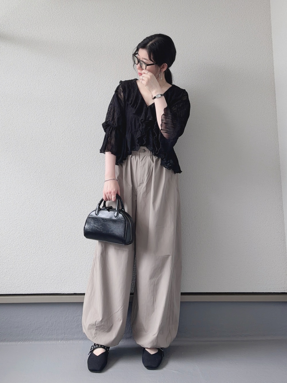 ブラック系のカーディガン/ボレロ、ベージュ系のパンツ、ブラック系のショルダーバッグを着用したレディースの夏コーディネートの1枚目の写真