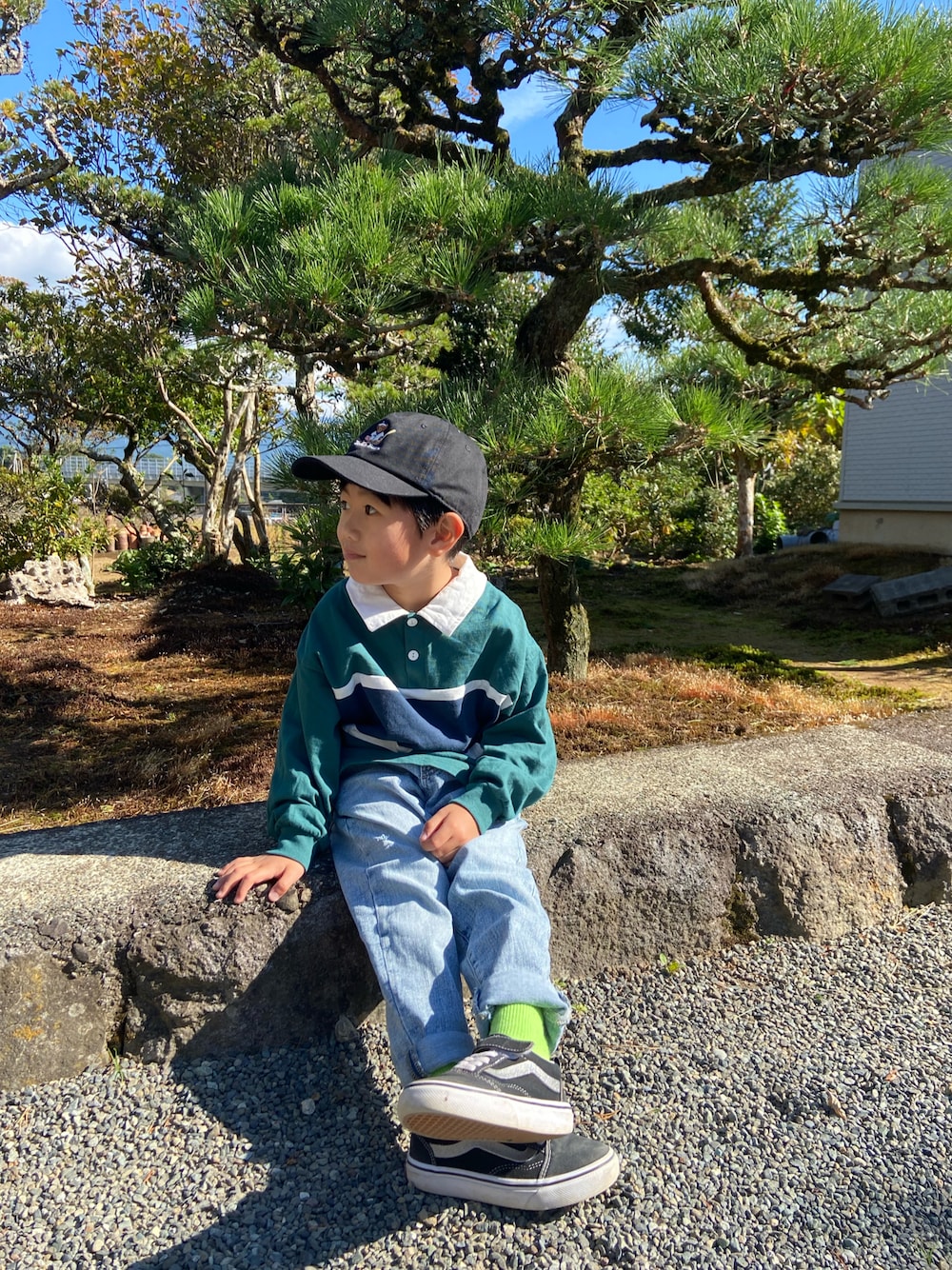グリーン系のTシャツ/カットソー、ブルー系のデニムパンツ、ブラック系のスニーカーを着用したキッズの秋コーディネートの1枚目の写真