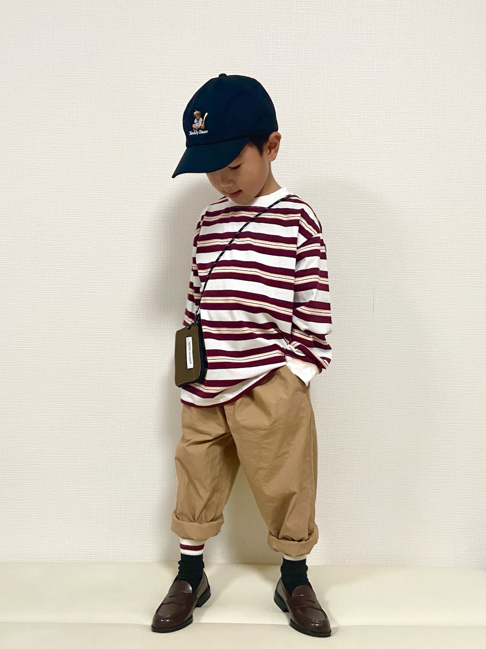 レッド系のTシャツ/カットソー、ベージュ系のその他パンツ、ブラウン系のローファーを着用したキッズの秋コーディネートの1枚目の写真