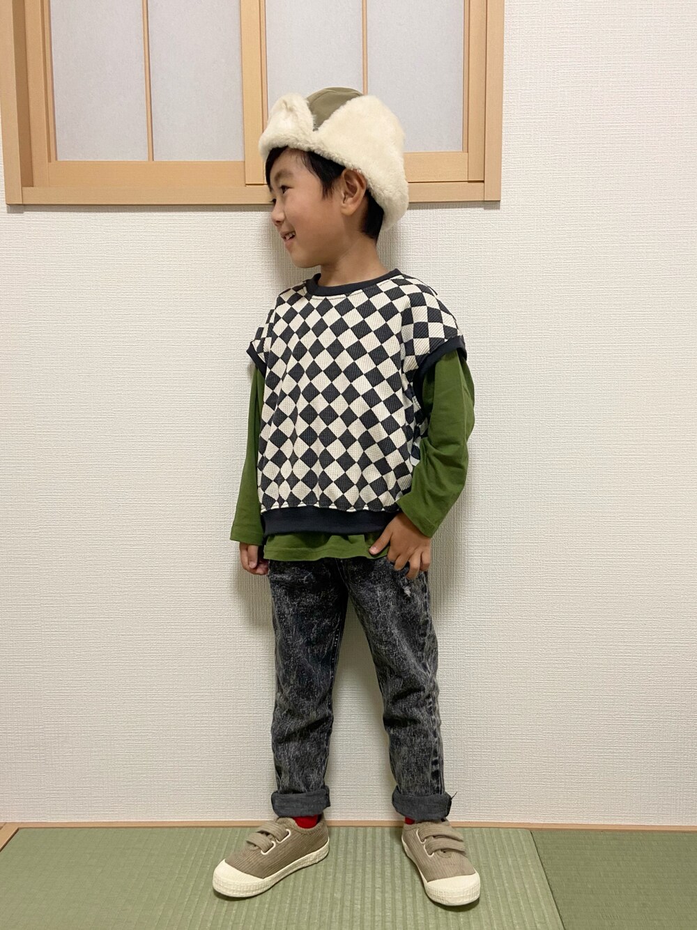 ブラック系のベスト、グリーン系のTシャツ/カットソー、ブラック系のデニムパンツを着用したキッズの秋コーディネートの1枚目の写真