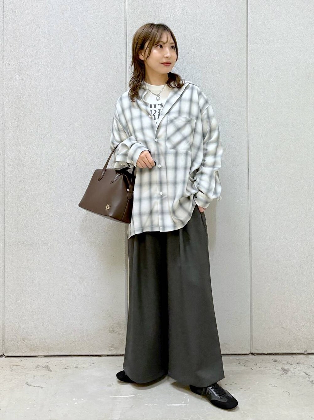 ホワイト系のTシャツ/カットソー、ブラウン系のショルダーバッグ、ブラック系のスニーカーを着用したレディースの冬コーディネートの1枚目の写真