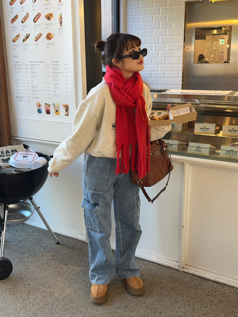 ブルー系のデニムパンツ、グレー系のスウェット、レッド系のマフラーを着用したレディースの冬コーディネートの1枚目の写真