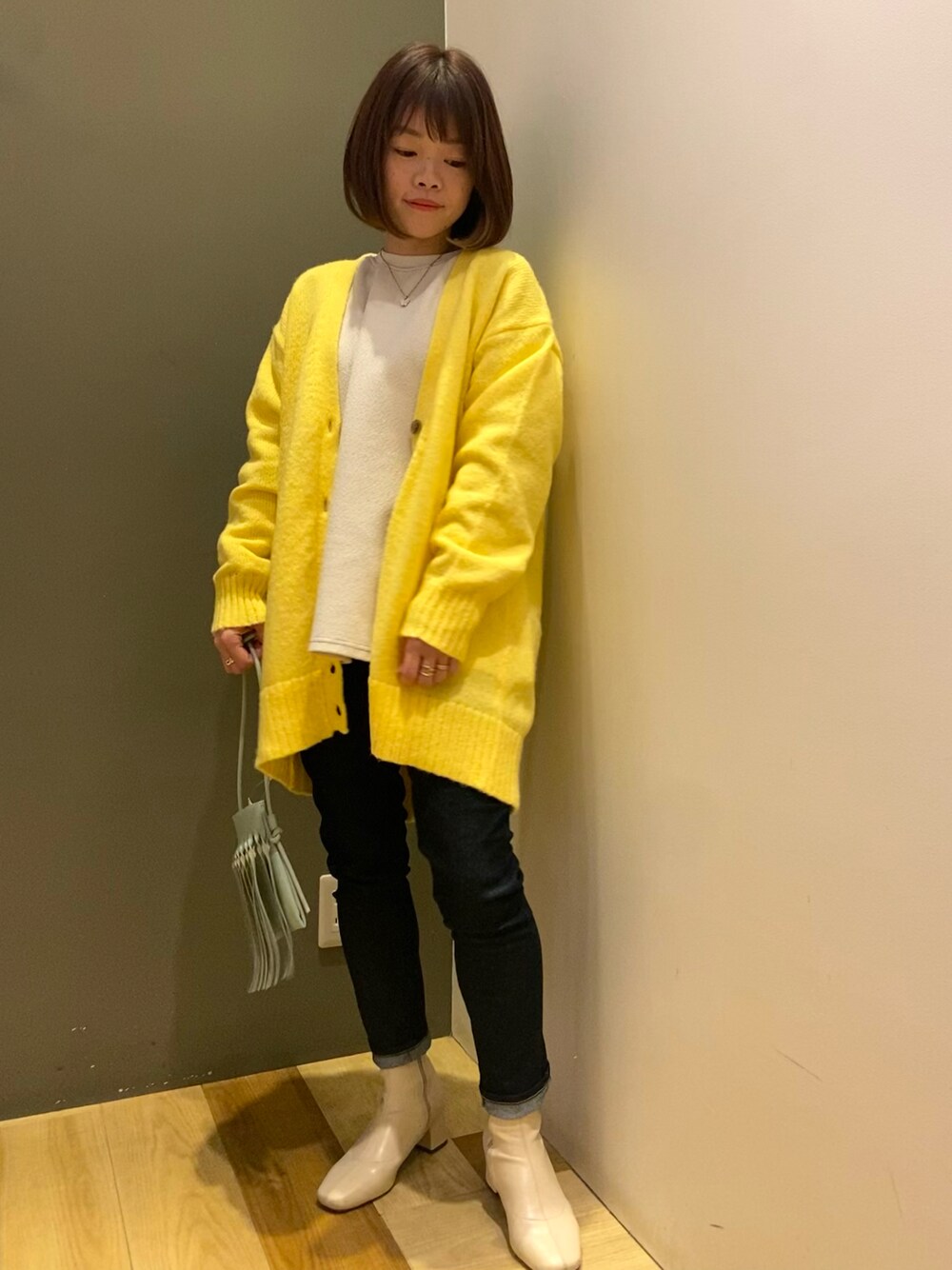 ホワイト系のTシャツ/カットソー、イエロー系のカーディガン/ボレロ、グリーン系のショルダーバッグを着用したレディースの冬コーディネートの1枚目の写真