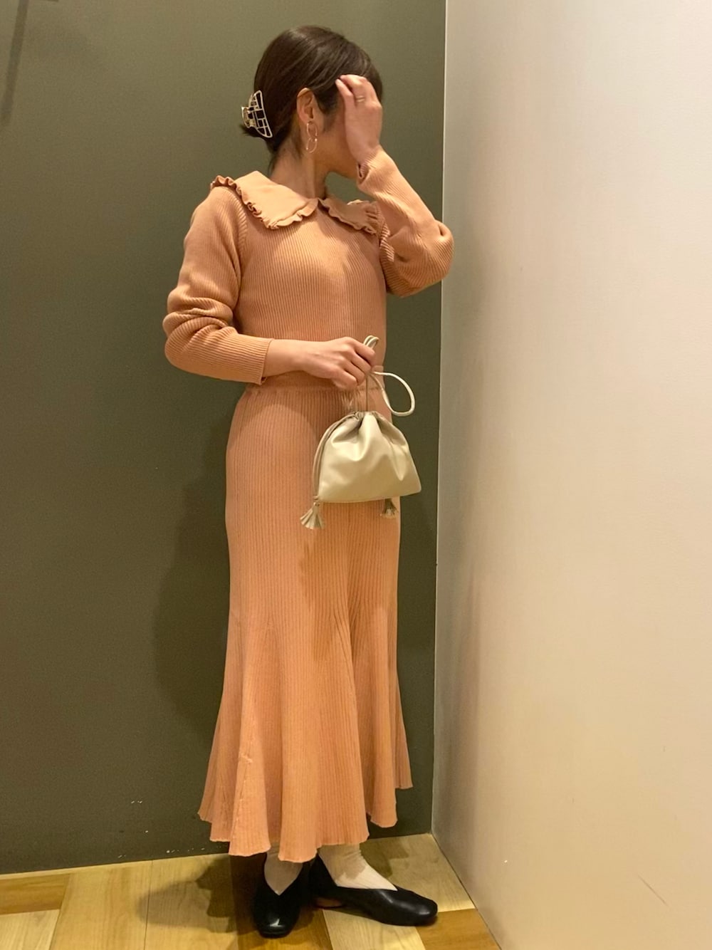 ピンク系のニット/セーター、ピンク系のスカート、ブラック系のパンプスを着用したレディースの冬コーディネートの1枚目の写真