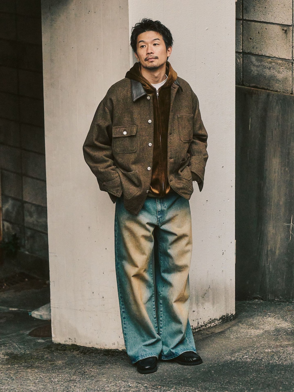 グリーン系のカバーオール、ブルー系のデニムパンツ、ブラウン系のパーカーを着用したメンズの冬コーディネートの1枚目の写真