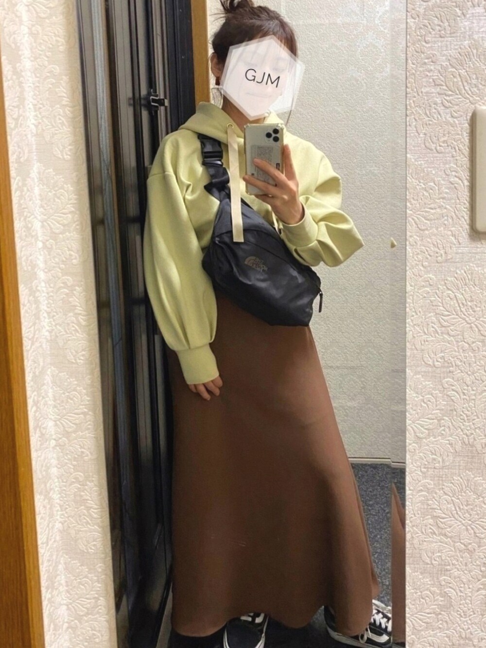 グリーン系のパーカー、ブラック系のボディバッグ/ウエストポーチ、ブラウン系のスカートを着用したレディースの冬コーディネートの1枚目の写真